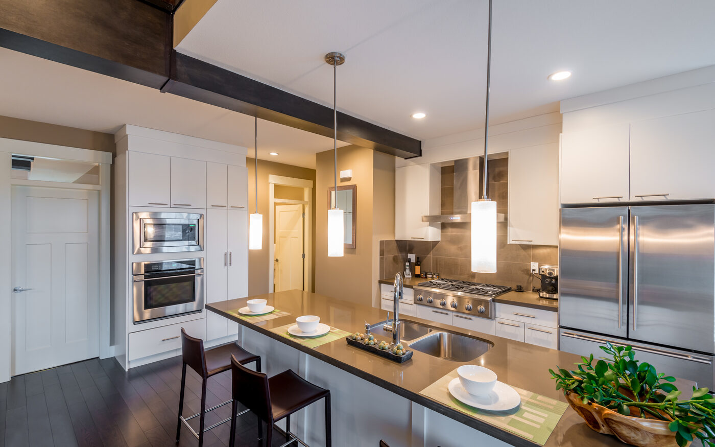 After: a bright modern kitchen with a large island, pendant lighting and stainless appliances