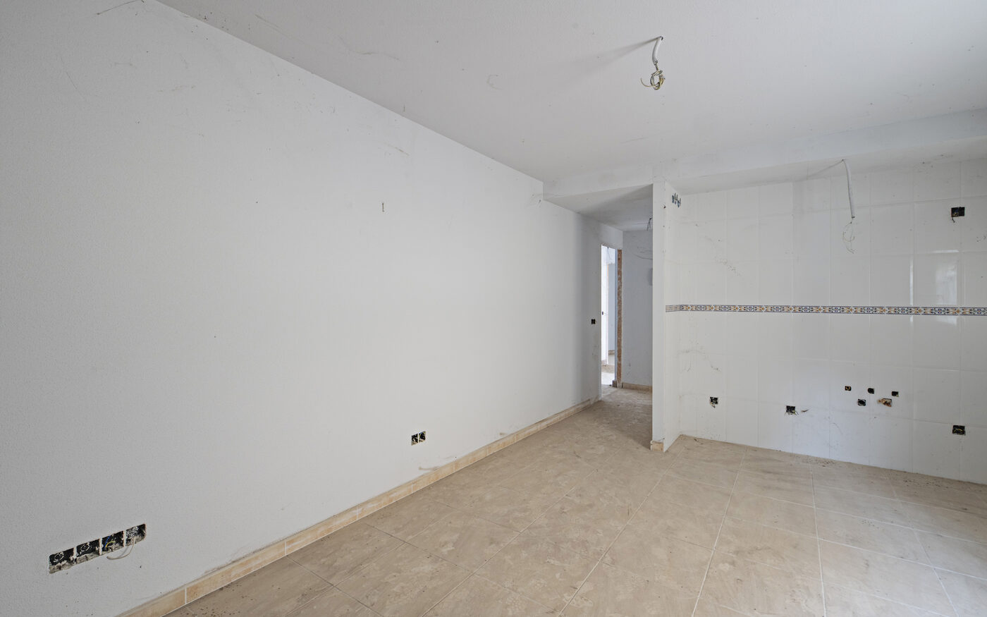 Before: a stripped, unfinished kitchen with bare tiled walls and exposed wiring