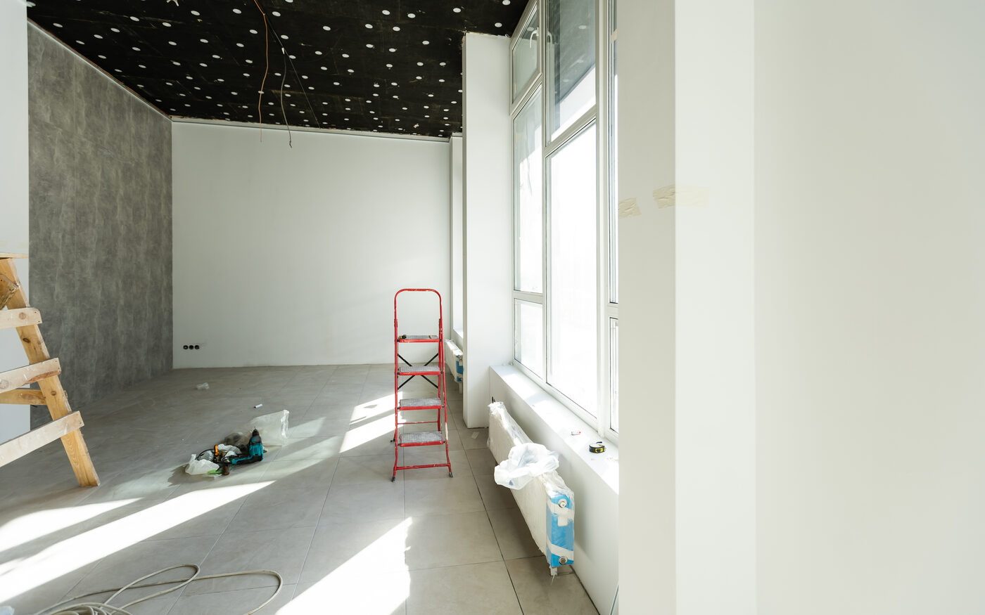Before: an enclosed room mid-construction with bare walls, a ladder and exposed ceiling